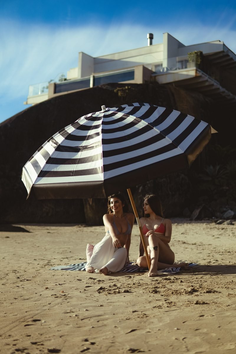 Guarda-sol listrado Rive na praia com modelos